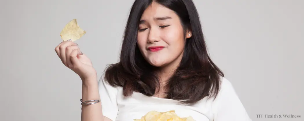 Picture of a sad woman eating a bowl of chips complementing the blog post "How to avoid emotional eating?"