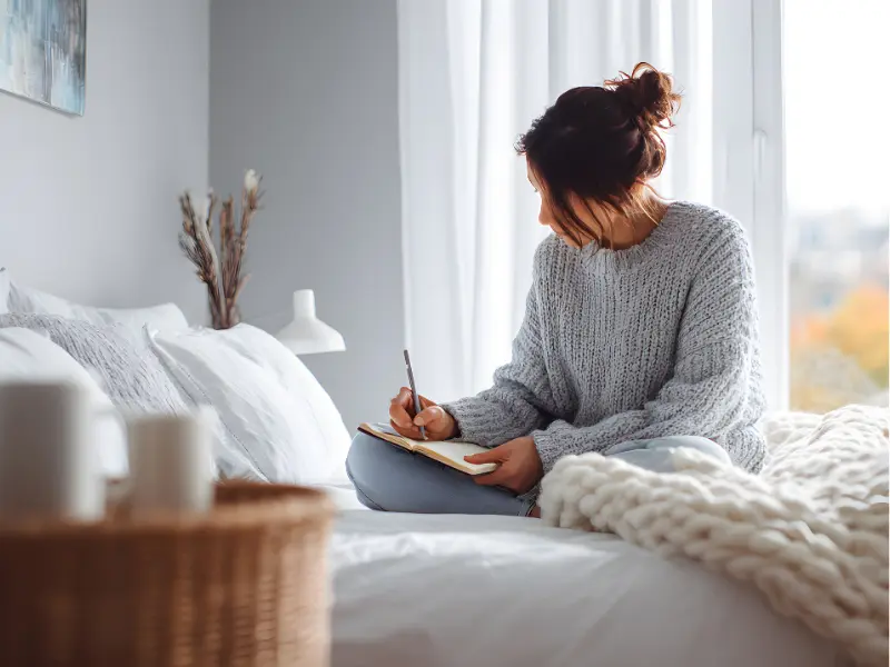 Woman journaling thoughtfully, practicing self-reflection and mindfulness to support inner voice transformation.